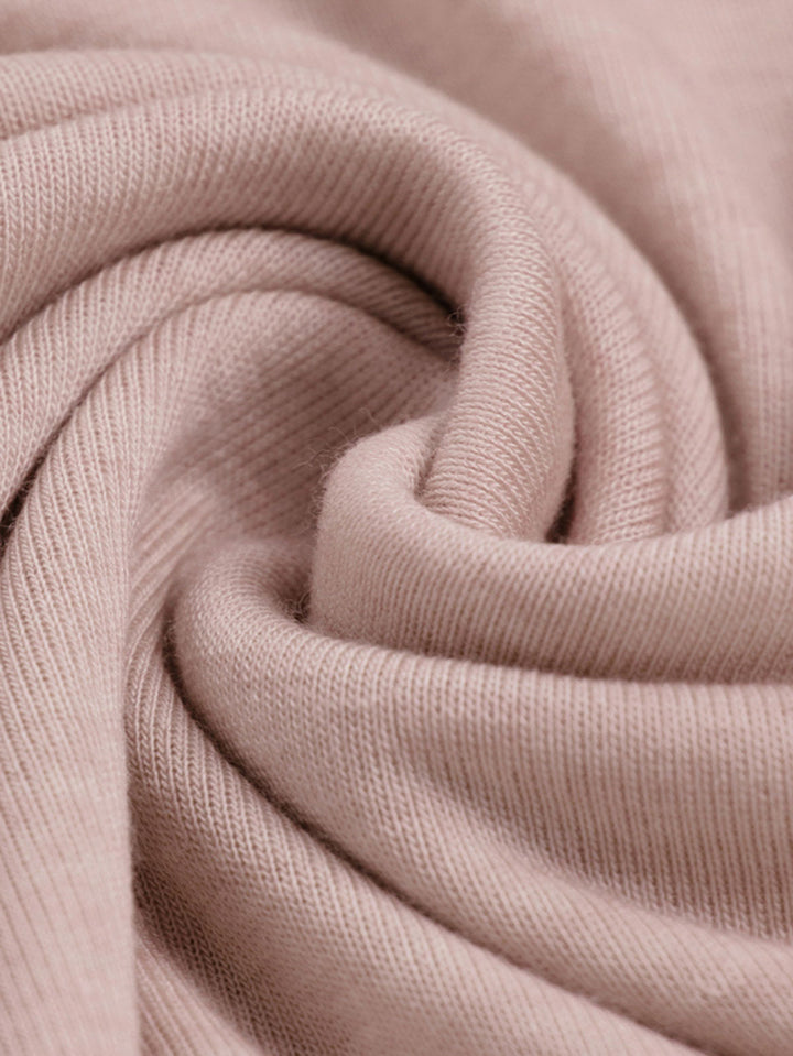 詳細画像: 薄霧ピンク配色ラグランスリーブスリムフィットTシャツの細部図。配色ラグランスリーブとダブルステッチのカーブヘムを展示。