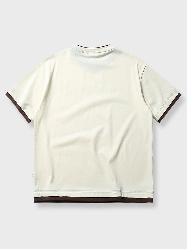 偽レイヤードプリントの半袖Tシャツ、クリアなメッセージとコントラストデザインが特徴的。