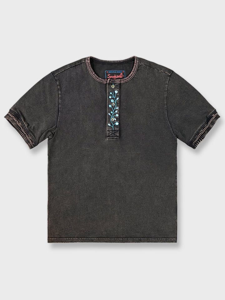 ヴィンテージ加工を施したヘンリーネック半袖シャツの正面ビュー、襟元と袖口に精密な刺繍が施されています。