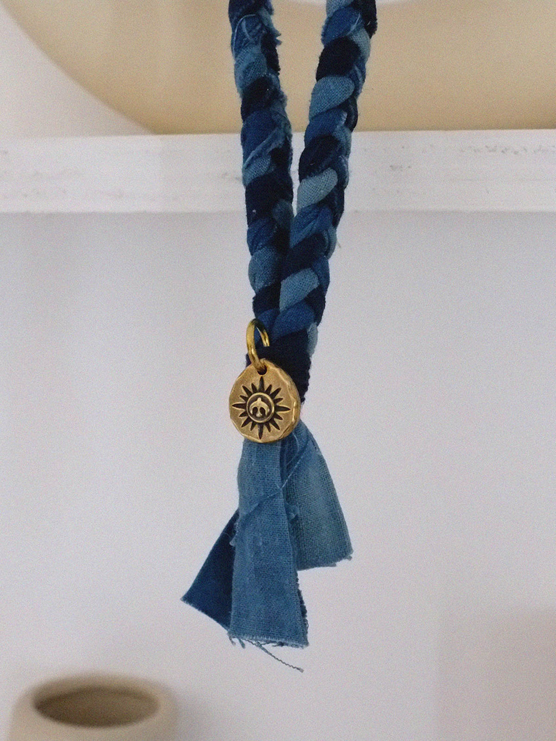 手作りで編み込まれた飛鳥コインのペンダントを持つ伝統的藍染めのネックレス。
