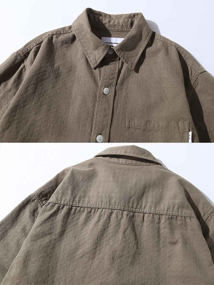 シンプルで洗練されたデザインの無地コットンワークシャツ正面ビュー。耐久性のある素材とフロントポケットが特徴。