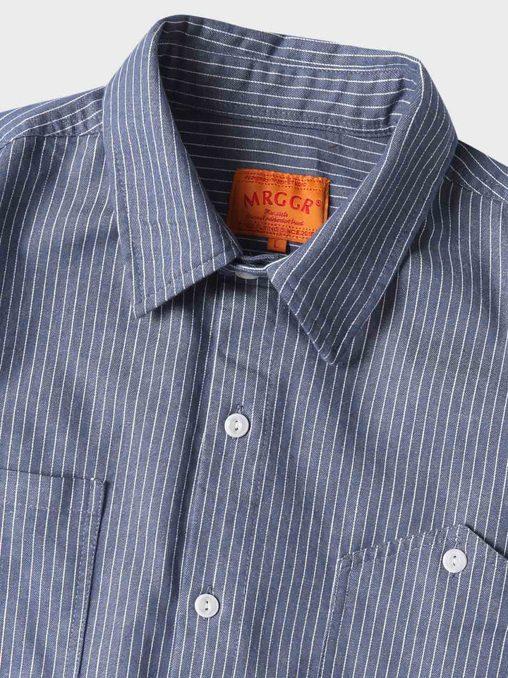 シャツの非対称ポケットと縦ストライプパターンのクローズアップ。70%コットンと30%ポリエステルの混紡ファブリックが見える。