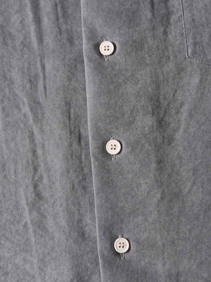 シャツのポリエステルとナイロンのブレンドファブリックをクローズアップで示す。優雅な光沢と抗しわ性を持つ素材。