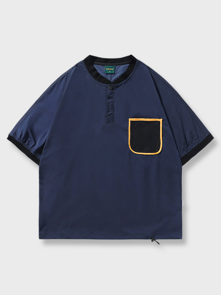 野球襟とフロントポケット付きの半袖Tシャツ。通気性が高く、調整可能な裾が特徴的で、カジュアルながらスポーティなスタイルを演出します。
