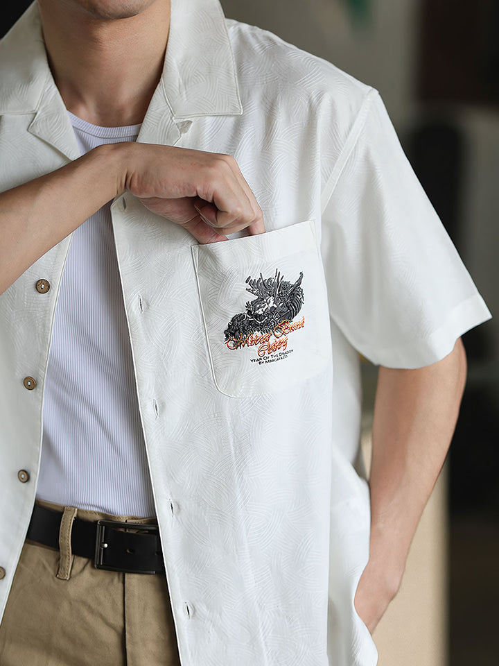 細部にわたるドラゴンの発泡プリント刺繍を特徴とするシャツのクローズアップ。