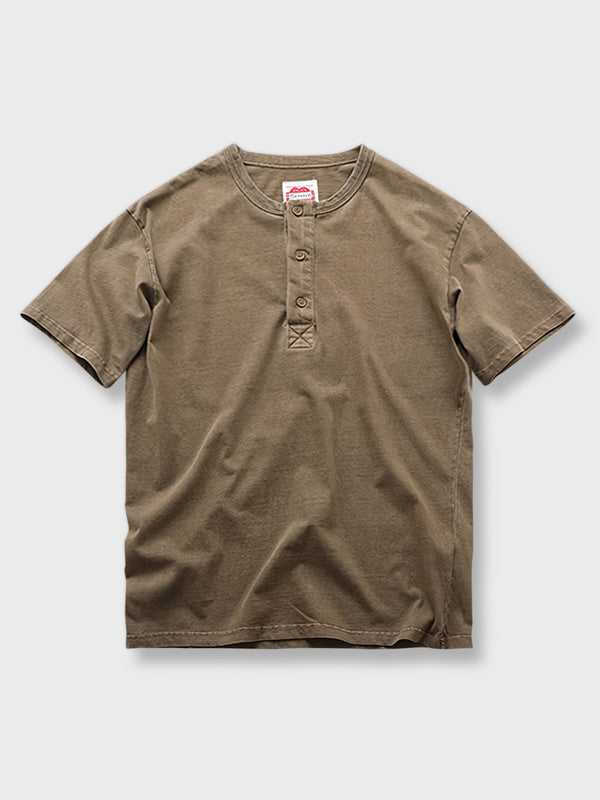 ヘンリーネックの半袖Tシャツ、ウォッシュ加工されたビンテージスタイルで280gのヘビーウェイトコットンが使用されている。単色背景にシンプルながらも洗練されたデザインが際立つ。