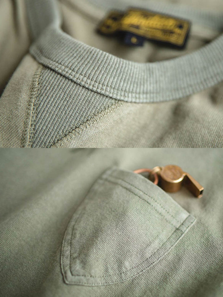 ヴィンテージミリタリーグリーンVネックポケットTシャツのVネック部分と胸ポケットの詳細。太いVネック補強が耐久性を向上させ、実用的な胸ポケットが付いており、重量感のあるコットン素材が使用されています。