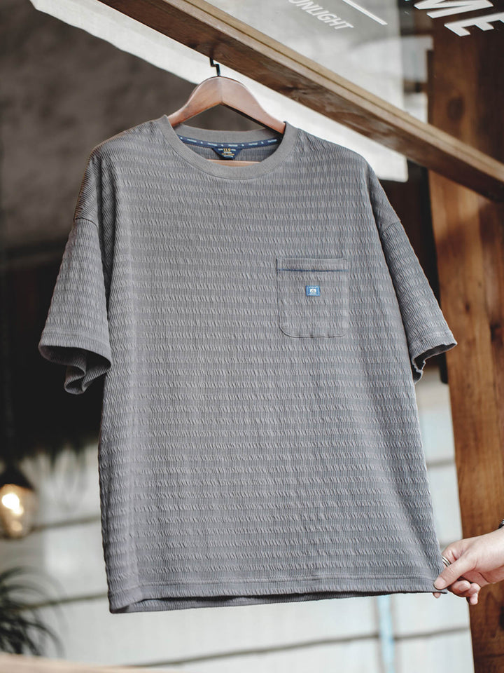 Tシャツの独特な波紋ニットテクスチャのクローズアップ。細かなディテールが視覚的にも層を形成しています。