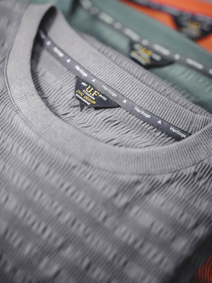 Tシャツの独特な波紋ニットテクスチャのクローズアップ。細かなディテールが視覚的にも層を形成しています。