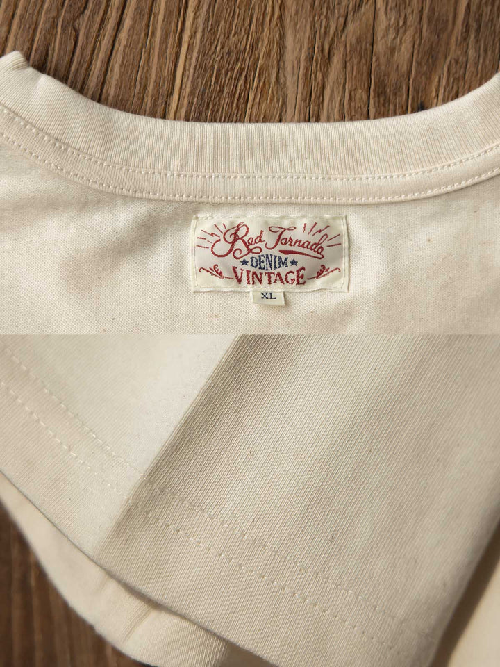純綿半袖Tシャツの精工ディテール、特に肩のチェーンステッチと裾及び袖のダブルステッチを強調するクローズアップ。耐久性と洗練された外見を提供します。