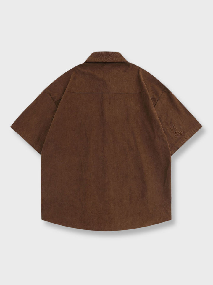 カフェ色の背景に鮮やかなローズ刺繍が施された半袖シャツ。軽やかで快適な100%ポリエステル素材を使用し、ゆったりとしたフィット感が特徴です。