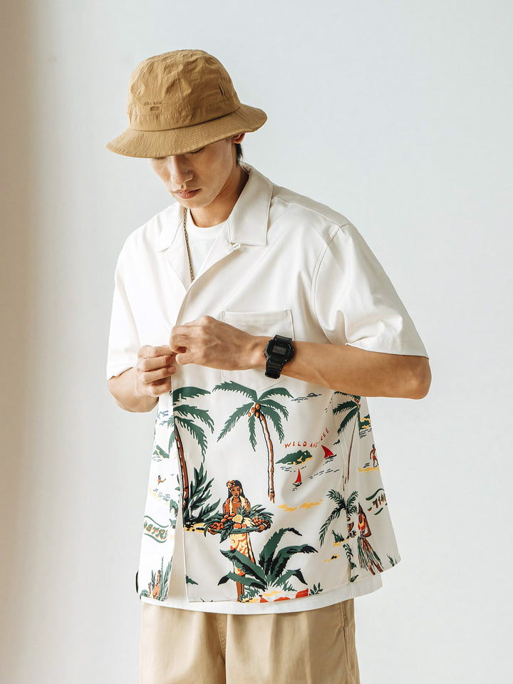 モデルが着用するビーチとヤシの木のレトロなハワイ風景プリントのアロハシャツ、自然で快適な着心地を示す。