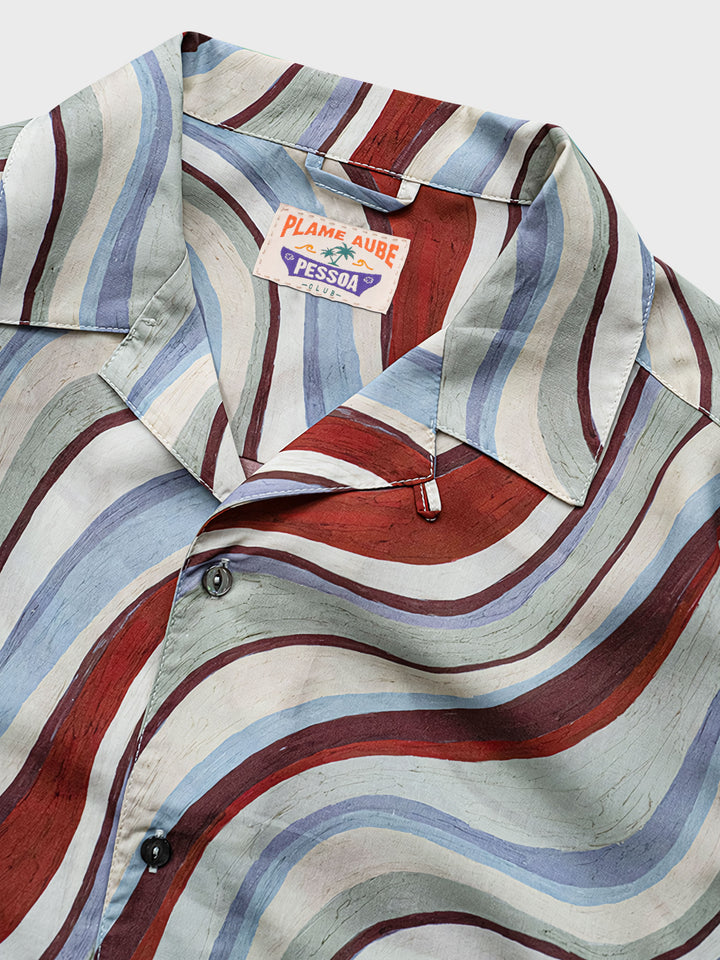 シャツの丸パールボタンの詳細、前短後長のスリットデザインと背中のプリーツでファッション性を高める