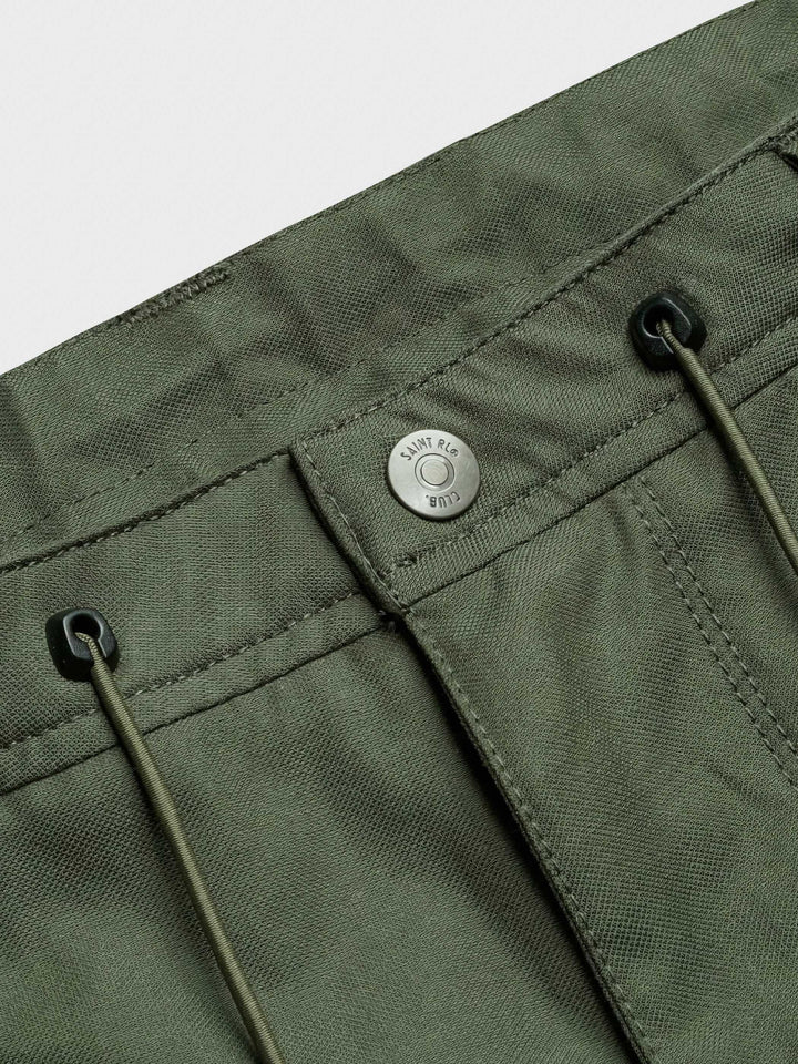 ショートパンツのフロントポケットの細部、バブルオーガンジーの立体的なアコーディオン構造と平和のシンボルが彫刻されたボタンのクローズアップ
