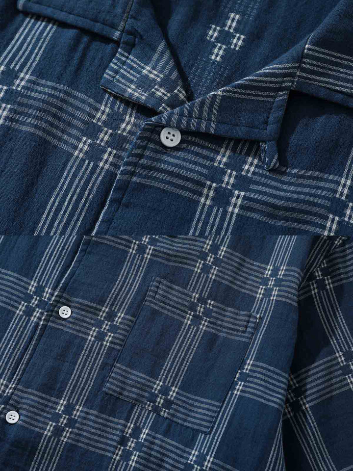チェック柄キューバンカラーシャツの細部、特に精緻に縫製されたポケットと洗練されたボタンディテールが特徴です。