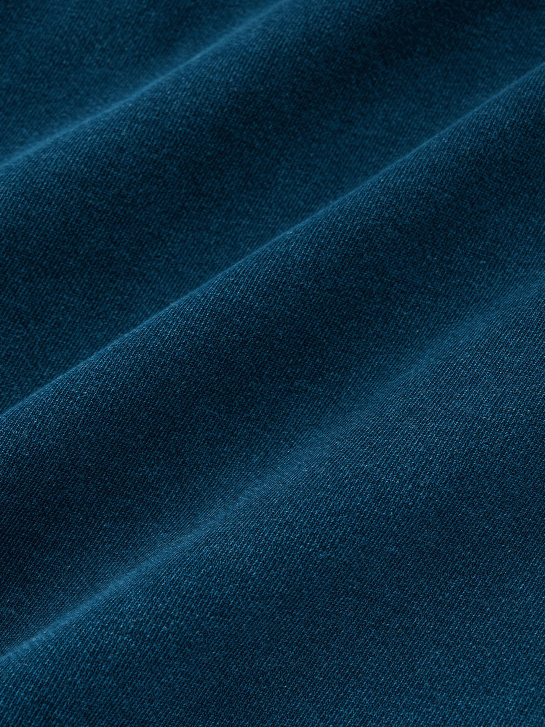 ウォッシュ加工が施された藍染めスウェットプルパーカの前面、紐付きデザインでレイヤー感を強調